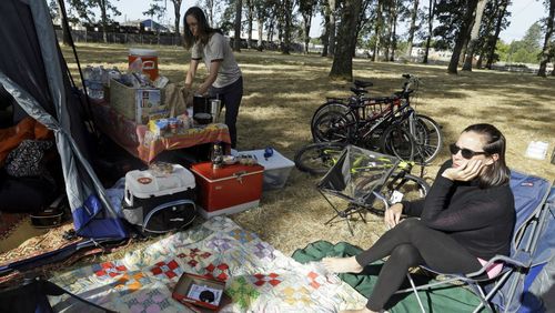 Hilary O'Hollaren, right, sits in the early morning sun as Rory O'Hollaren prepares breakfast as they camp near the state fairgrounds in preparation for the eclipse. (AAP)
