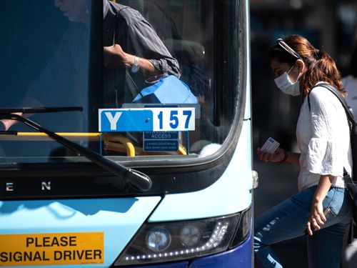 A woman wearing a protective face mask boards a bus in Sydney