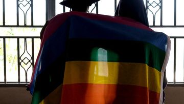 A gay Ugandan couple cover themselves with a pride flag