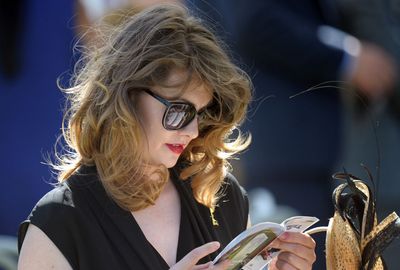 A woman checks the guide book before the next race. (AAP)