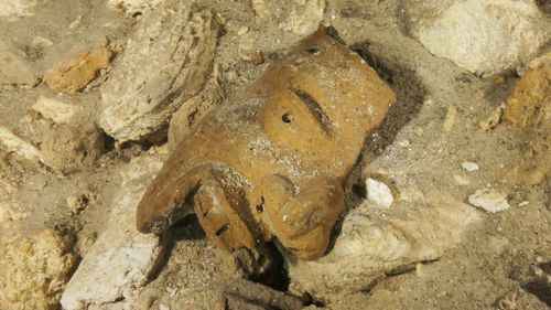 Undated photo released by Mexico's National Anthropology and History Institute (INAH) shows a piece of a broken mask on the cave floor inside the Sac Actun underwater cave system. (AAP) 