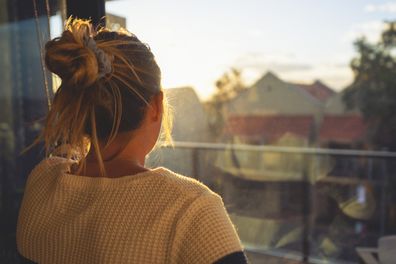 Woman looking out window, depressed.