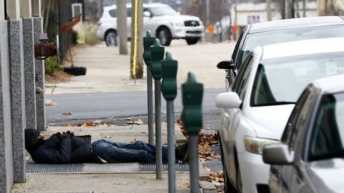 A homeless man warms himself over a vent in the footpath to stay warm in Jackson, Missouri. At least a dozen people have died from exposure during the brutal cold snap.
