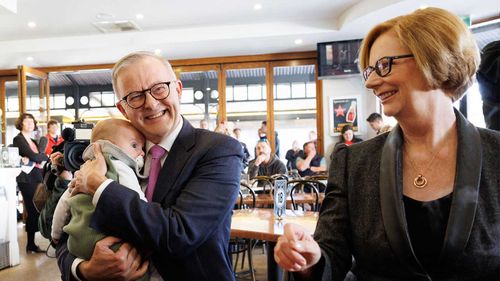 Anthony Albanese cradles Mark Butler's son Charlie as Julia Gillard looks on.