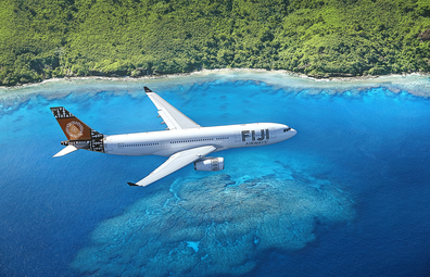 Fiji Airways plane flying over blue water along the Fiji coast