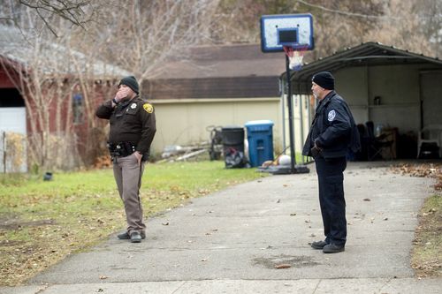 An Oakland County Sheriff's Deputy, left, and Oxford police officer search the grounds outside of the Crumbley residence while seeking James and Jennifer Crumbley, parents of the alleged Oxford High School shooter, on Friday, Dec. 3, 2021 in Oxford.