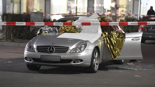 A car that was damaged in a shooting is covered in thermo foil is parked in front of a bar at the scene in Hanau, Germany.