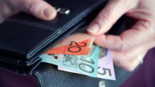 Mão feminina de mulher adulta tirando dinheiro australiano de uma carteira de couro.