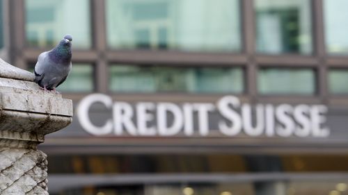 FILE - A pigeon rests near a building hosting offices of Credit Suisse bank in Milan, Tuesday, Oct. 27, 2009. 