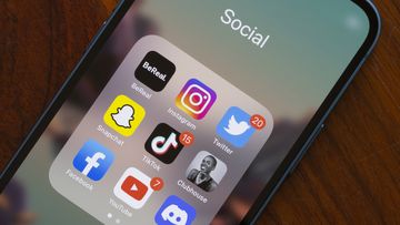 Assorted popular social media apps - BeReal, Instagram, Twitter, Snapchat, TikTok, Clubhouse, Facebook, YouTube, and Discord - are seen on an iPhone. 