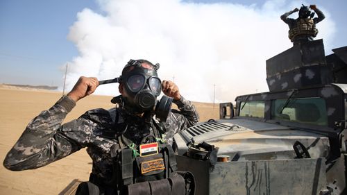 Iraqi forces wear gas masks for protection as smoke billows in the background after Islamic State (IS) group jihadists torched Mishraq sulphur factory, about 30 kilometres south of Mosul. Toxic fumes released when jihadists torched a sulphur plant near Mosul have killed two Iraqi civilians, made many ill and forced US troops at a nearby base to wear masks.

AHMAD AL-RUBAYE / AFP