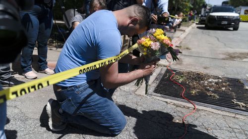Joseph Avila prays while holding flowers in honor of the victims killed in the Robb Elementary School shooting in Uvalde, Texas.