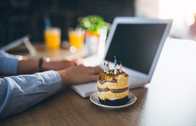 Office birthday cake while typing on a laptop computer at desk