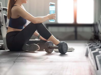 Woman in the gym wearing sports bra taking a break