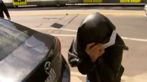The accused shielded her face outside a police station. (9NEWS)