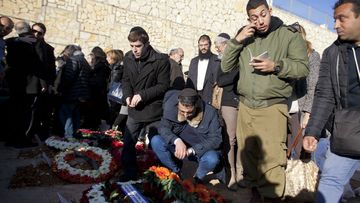 Mourners stand next to the graves of four Jews killed in an Islamist attack on a kosher supermarket in Paris on January 13. (Getty Images)