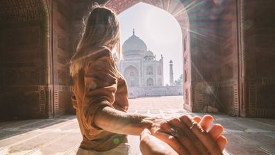 Follow me to the Taj Mahal, India. Female tourist leading boyfriend to there magnificent famous Mausoleum in Agra. People travel concept