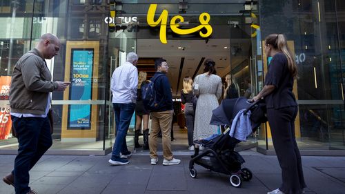 Customers line up outside an Optus shop fron