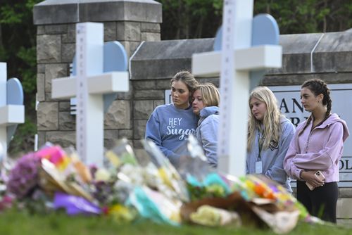 دانش‌آموزان مدرسه‌ای در نزدیکی در محل یادبود افرادی که کشته شدند، در ورودی مدرسه کووننت، سه‌شنبه، 28 مارس 2023، در نشویل، تن ادای احترام می‌کنند.