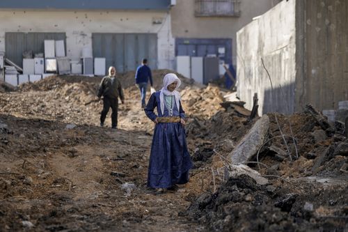 Palestinians walk on a damaged road following an Israeli military raid in Jenin refugee camp, West Bank, Friday, Nov. 17, 2023.  