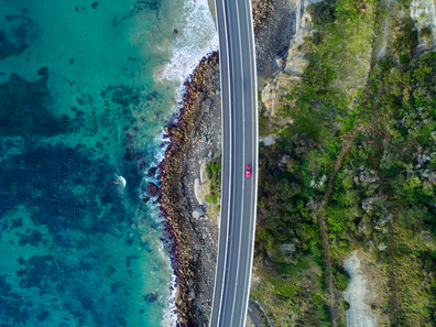 Aerial view of car driving over Sea Cliff Bridge on NSW coast