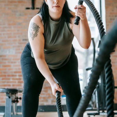 Stock image of a woman in the gym using ropes to work out.