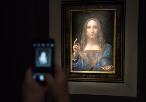 A visitor takes a photo of the painting 'Salvator Mundi' by Leonardo da Vinci at Christie's New York Auction House. (Getty)