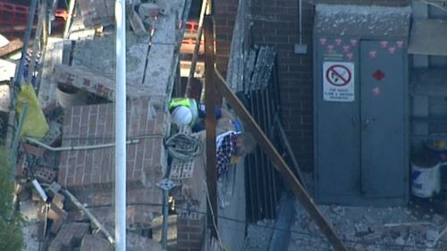 Emergency services trying to free a man from the rubble, after a wall collapse. (9NEWS)