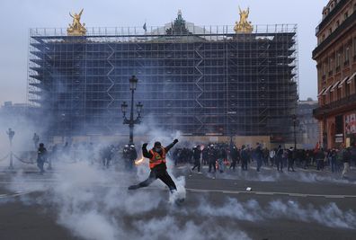 A protester kicks a tear gas canister in front of the Opera at the end of a rally in Paris, Thursday, march 23, 2023. 