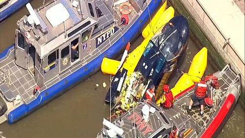 Screenshot from WABC-TV video shows units from the New York City police and fire departments work to secure a helicopter to the dock after it crashed in the Hudson River.