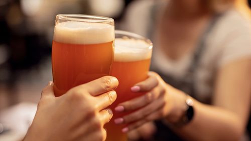 Two people toasting beer in a bar