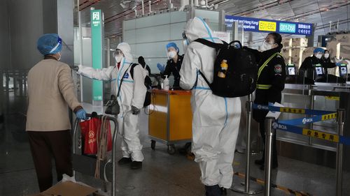 보호 장비를 착용한 승객들이 2022년 12월 13일 화요일 베이징의 수도 공항 터미널에서 비행기로 향하고 있습니다. 일부 중국 대학은 COVID의 확산 가능성을 줄이기 위해 학생들이 집에서 학기를 마치도록 허용할 것이라고 말했습니다. -19년 1월 설날 여행 러시 때 발생. .