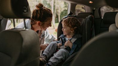 Photo of two boys, brothers, getting ready for a car road trip with their mom