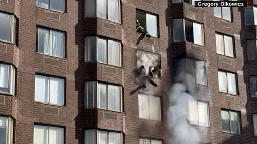 The woman was seen dangling out a window as FDNY fire fighters worked to rescue her.