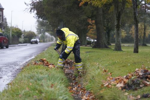 A workman clears a drainage ditch in the village of Edzell, Scotland, ahead of Storm Babet, Thursday Oct. 19, 2023.  