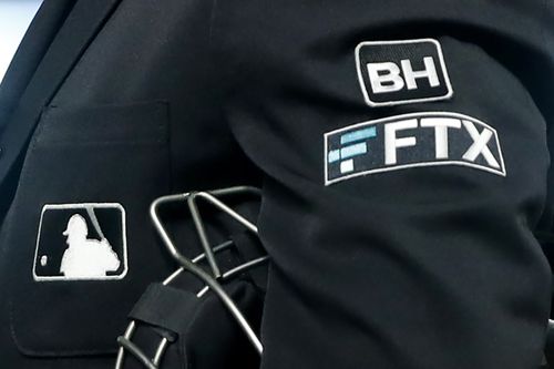 O logotipo da FTX é visto na jaqueta de um árbitro da home plate durante um jogo de beisebol com o Minnesota Twins em 27 de setembro de 2022 em Minneapolis.  A empresa de negociação de criptomoedas implosiva FTX agora está com falta de bilhões depois de experimentar o equivalente criptográfico de uma corrida bancária. 