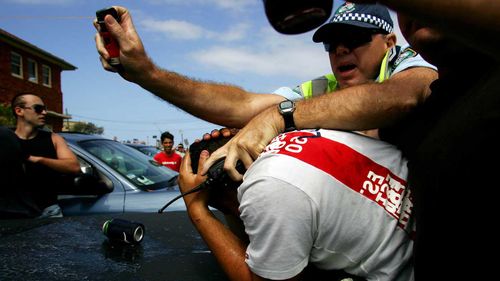 A police officer tries to protect a non-white man set upon by riots in 2005.