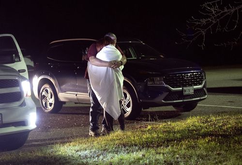 A woman is hugged by a man at a reunification center at Auburn Middle School, in Auburn, Maine, after shootings in Lewiston on Wednesday, Oct. 25, 2023. 