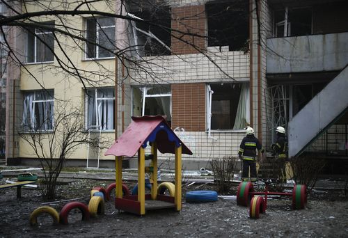 Rescuers stand at the scene where a helicopter crashed on civil infrastructure in Brovary, on the outskirts of Kyiv, Ukraine, Wednesday, Jan. 18, 2023. 