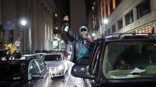 A Philadelphia Eagles fan holds a champagne bottle out a car window. (AAP)