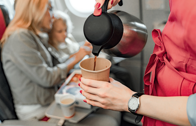 Flight attendant pouring a coffee during plane service