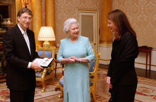 Queen Elizabeth II presents Bill Gates with an honorary knighthood in 2005, as his wife Melinda watches on.