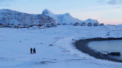 Two people walk along a beach in Nuuk, the capital of Greenland.