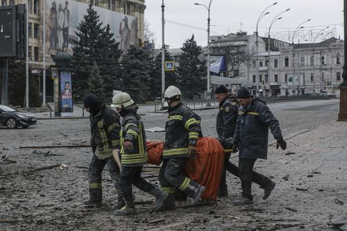 Ukrainian emergency service personnel carry a body of a victim following shelling that hit the City Hall building in Kharkiv, Ukraine, Tuesday, March 1, 2022. 
