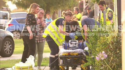 A woman cries as she watches paramedics care for the child. (9NEWS)