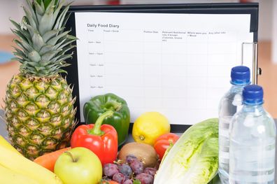 A food diary surrounded by fruits and vegetables to promote healthy eating.