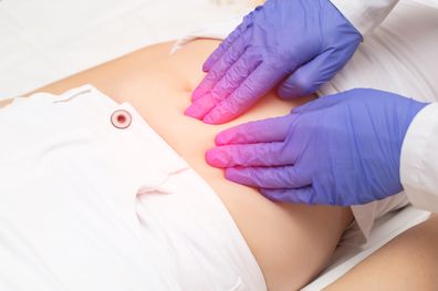 A gynecologist doctor probes the lower abdomen of a girl who has pain and inflammation of the reproductive system. Ovarian cyst