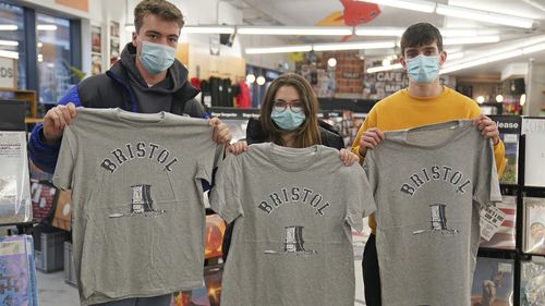 Customers inside Rough Trade in Bristol, England, Saturday Dec. 11, 2021, hold T-shirts designed by street artist Banksy