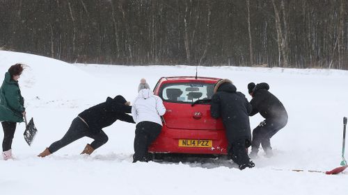 A car is pushed in snowy conditions in Larbert, near Falkirk, as storm Emma, rolling in from the Atlantic, looks poised to meet the Beast from the East. (AAP)