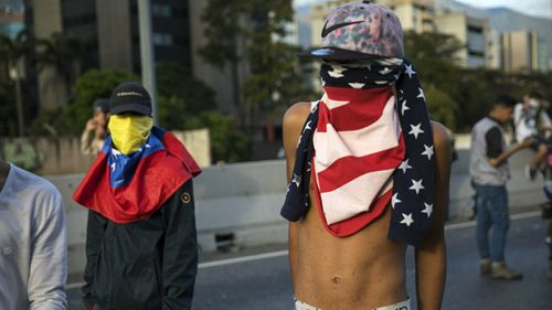 An anti-government protester using a US flag as a mask stands with a small group of demonstrators who were returning from a peaceful demonstration called by self-declared interim president Juan Guaido to demand the resignation of President Nicolas Maduro, in Caracas, Venezuela.